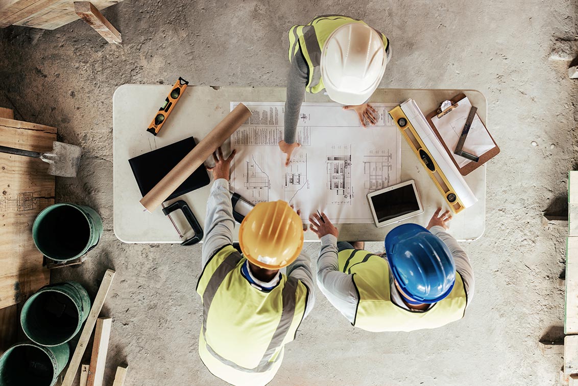 Men in hard hats looking over a schematic